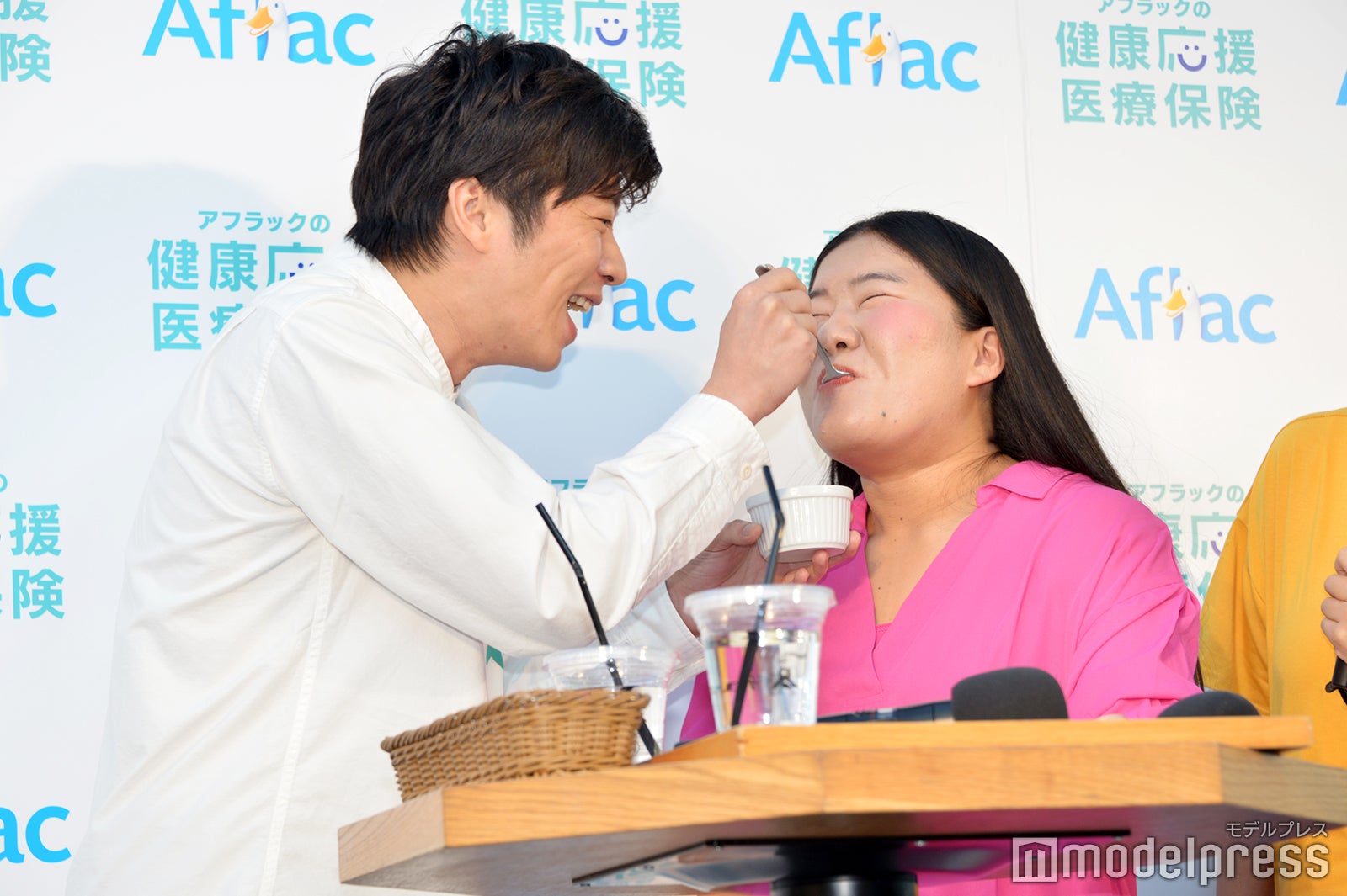 よしこ（右）に激苦健康卵豆腐を“あ～ん”する田中圭（左）／（C）モデルプレス