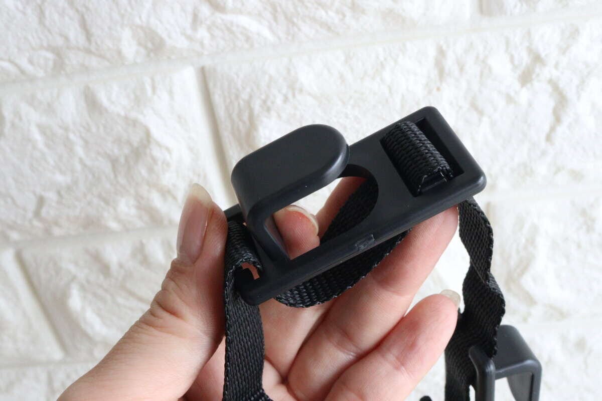 女性の手がヘッドレスト用お買い物フックの固定パーツを指す 女性の手がヘッドレスト用お買い物フックの固定パーツを指す