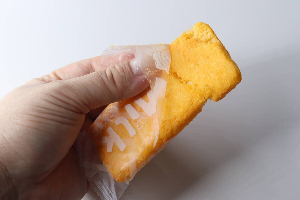 手がチーズ味ライスクラッカーの個包装を開けている様子