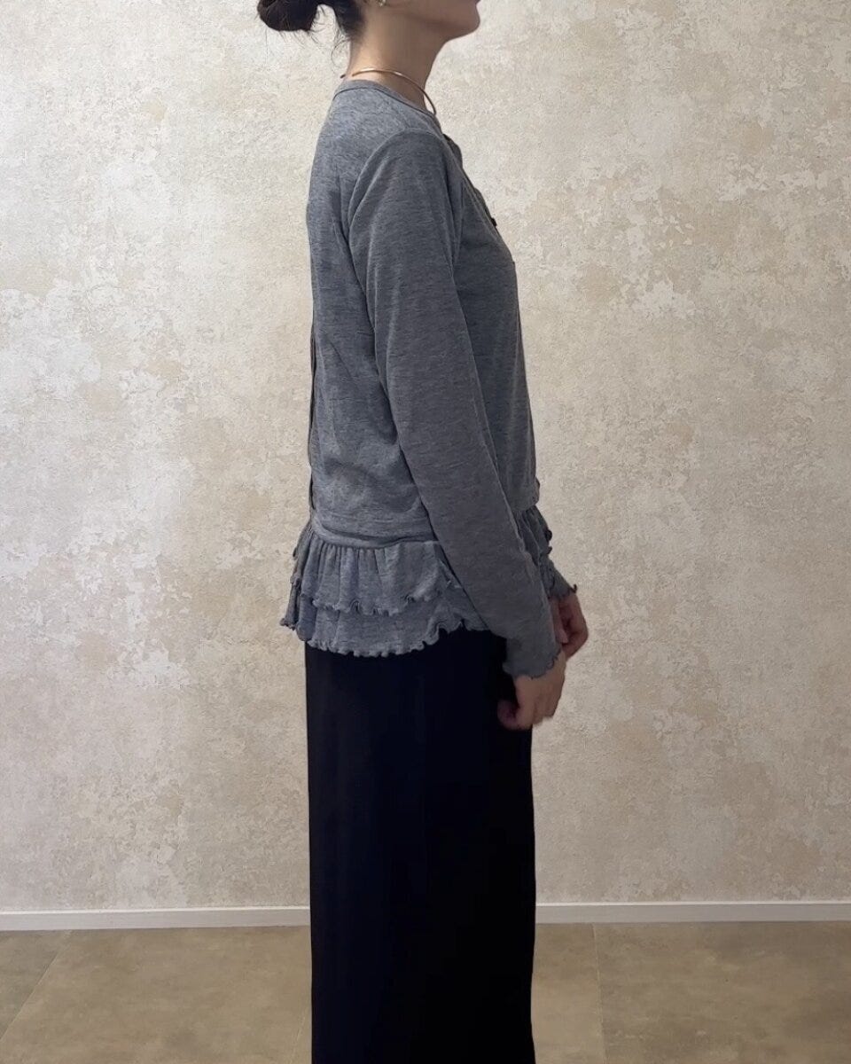 グレーのカーディガンと黒のロングスカートを着用した女性の横向き