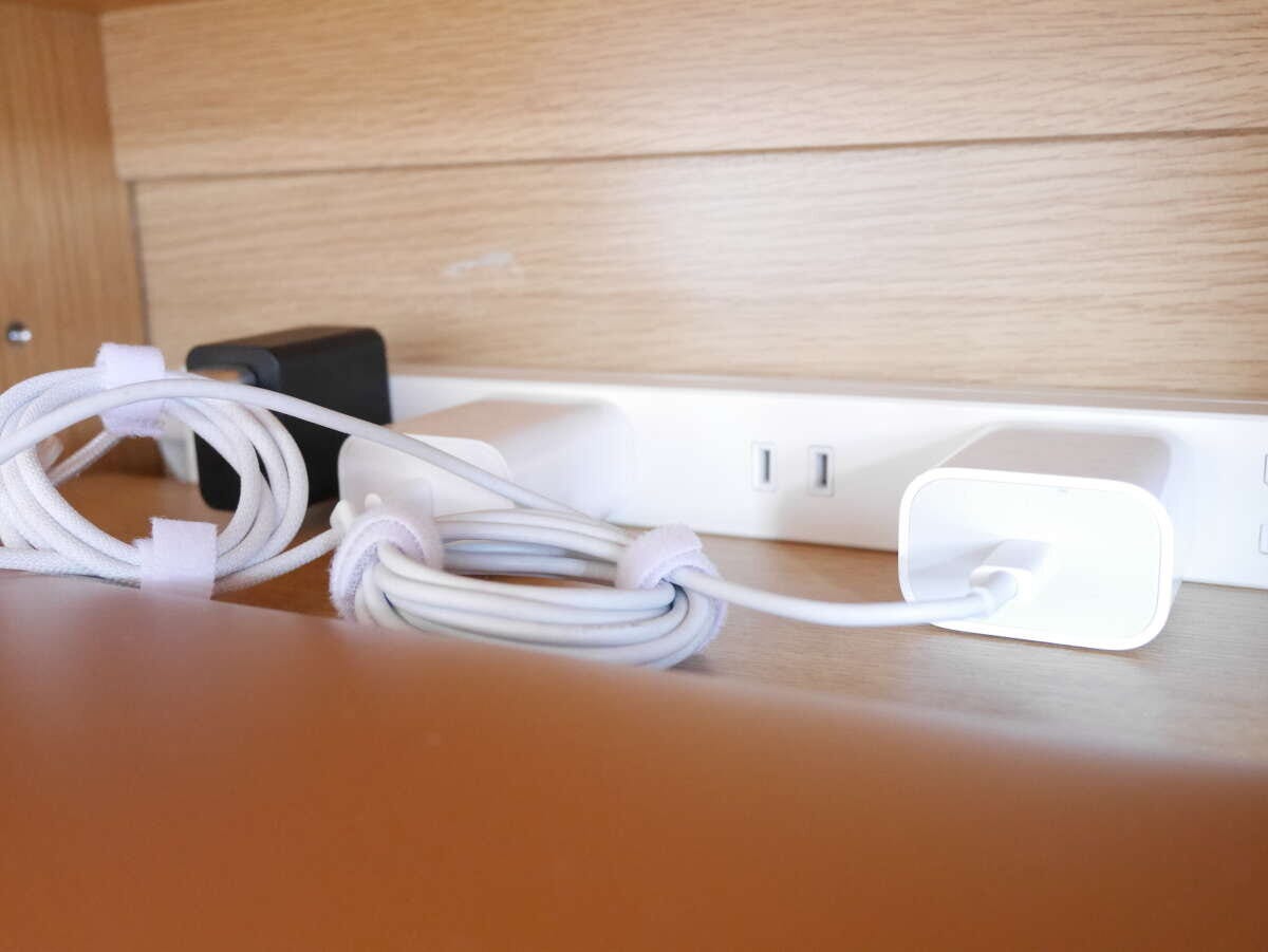 テレビ台の裏で白い電源タップにまとめた白いコードをマジックテープで留めている様子 テレビ台の裏で白い電源タップにまとめた白いコードをマジックテープで留めている様子