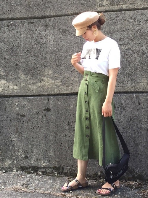 白のプリントTシャツにカーキのボタンスカートを履いた女性