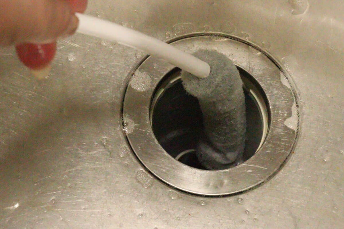 キッチンのステンレス製排水口に排水管ブラシを差し込んでいる