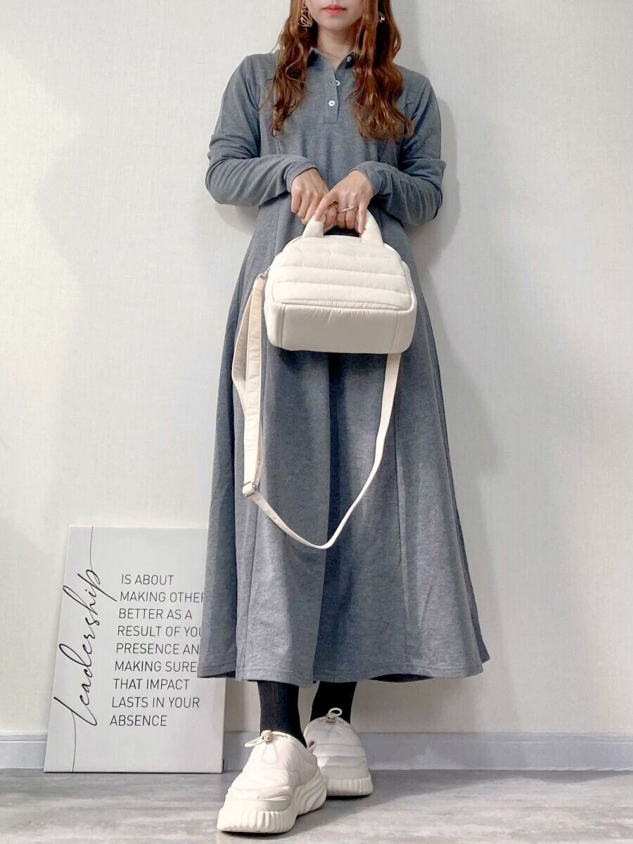 グレーのワンピースを着た女性が白いバッグを手持ちしている全身コーデ
