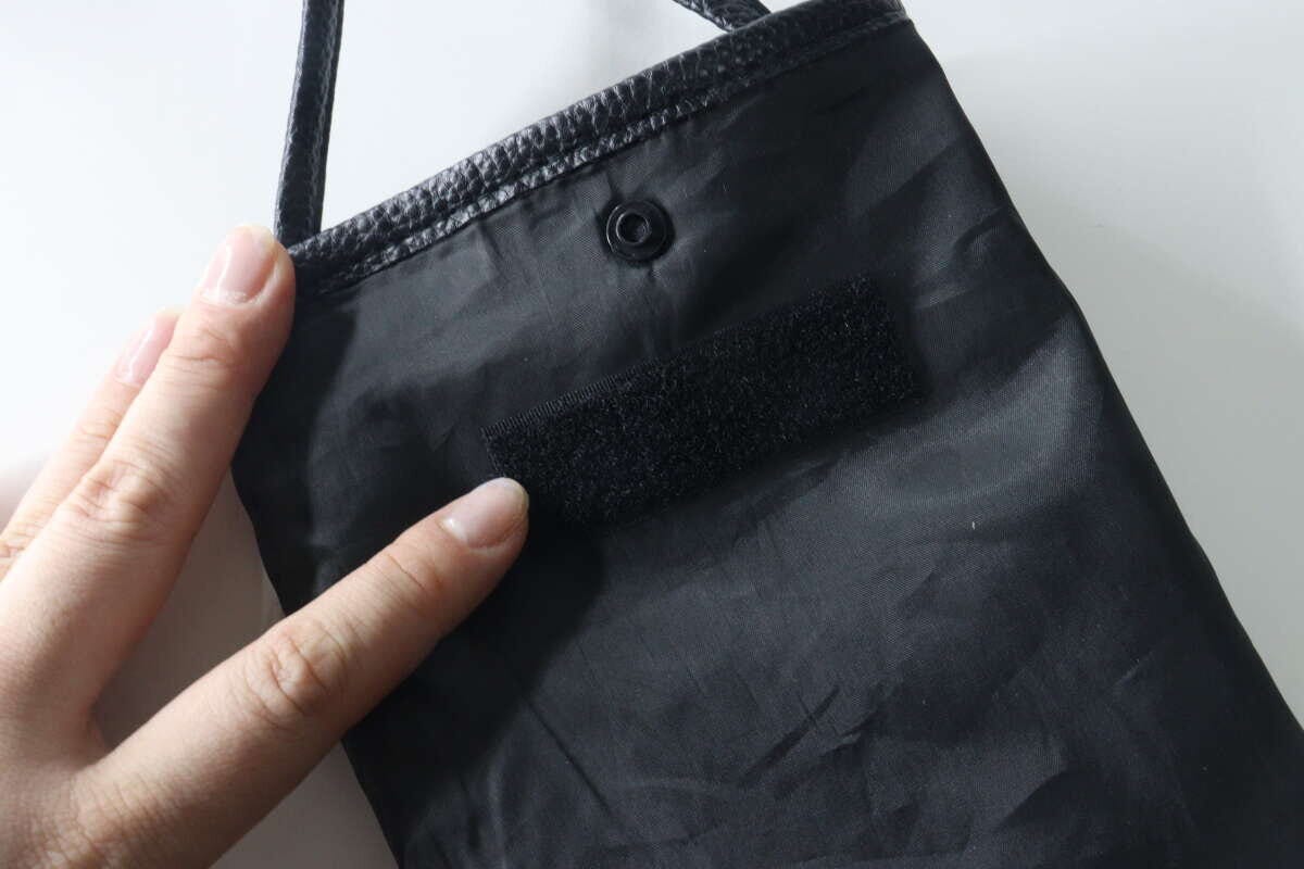 女性が黒いサコッシュの内側に面ファスナーを貼っている 女性が黒いサコッシュの内側に面ファスナーを貼っている