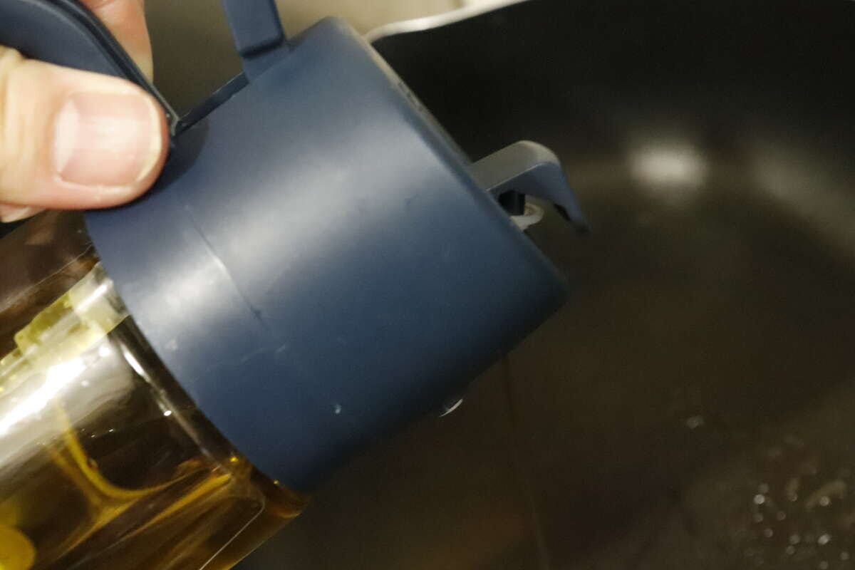 フライパンにオイルを注いでいる手元