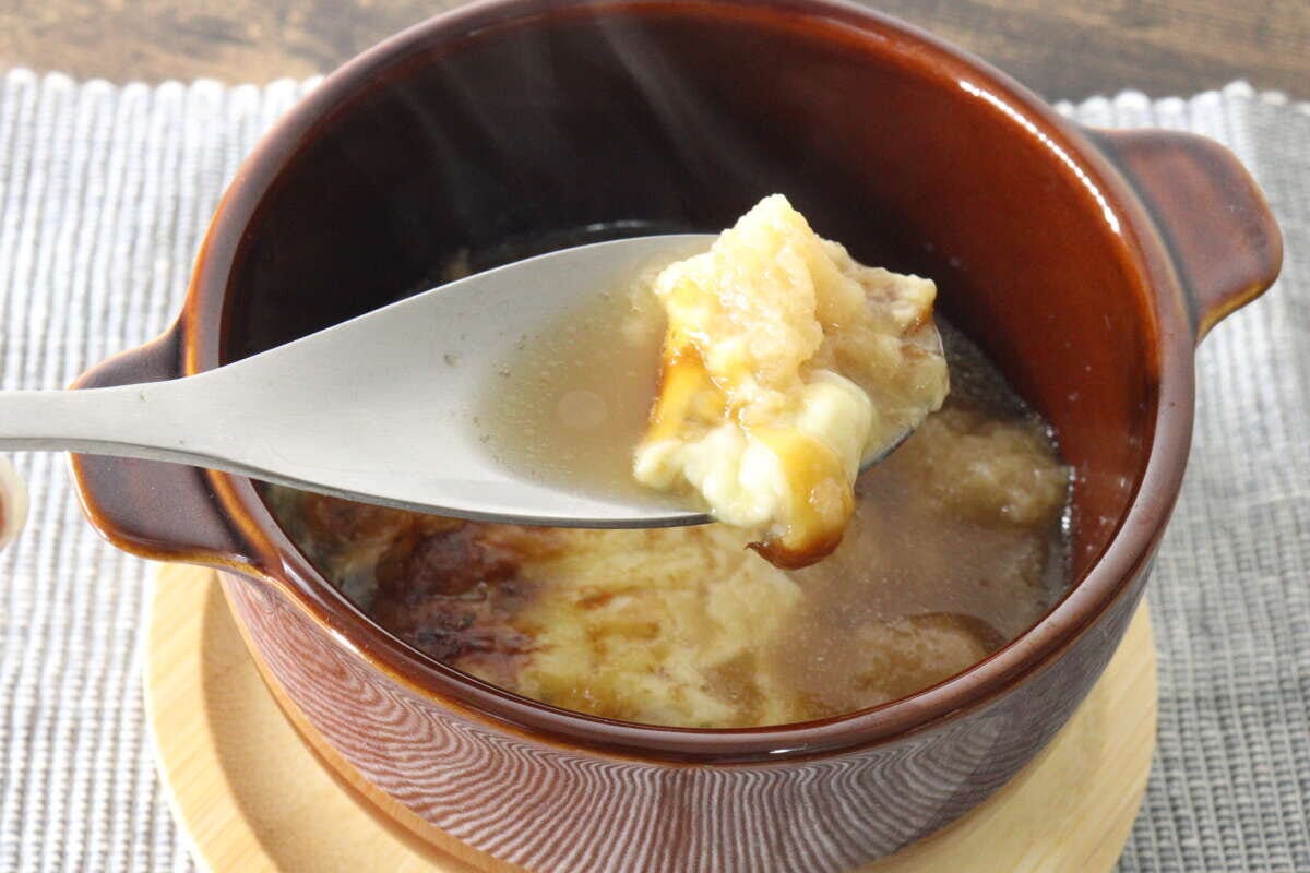 スープボウルからスプーンでとろけたチーズをすくい上げている様子