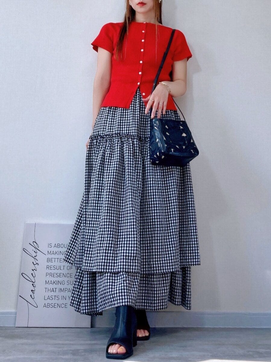 赤いカーディガンとギンガムチェックスカートを合わせた女性の全身