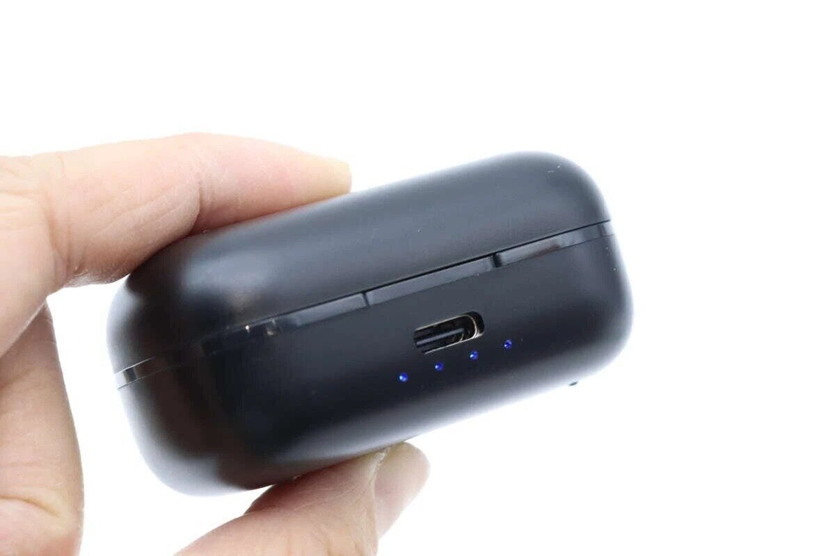 指で持った黒いワイヤレスイヤホンの充電ケース。充電ポートと青いLEDが見える 指で持った黒いワイヤレスイヤホンの充電ケース。充電ポートと青いLEDが見える