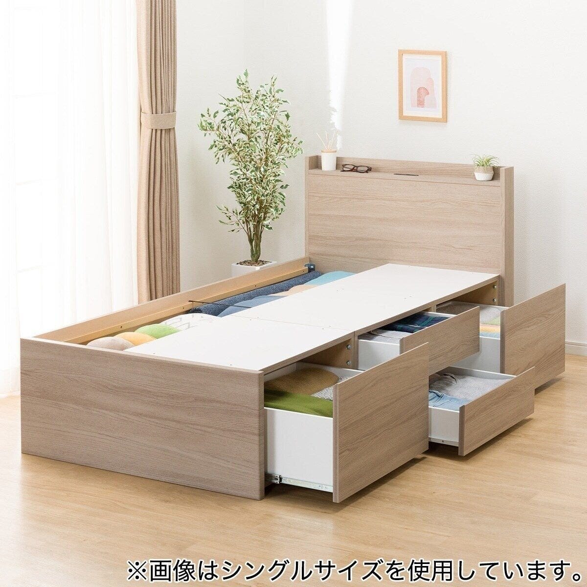 木目調のチェストベッドフレーム。引き出しが複数開いており、収納されている衣類が見える