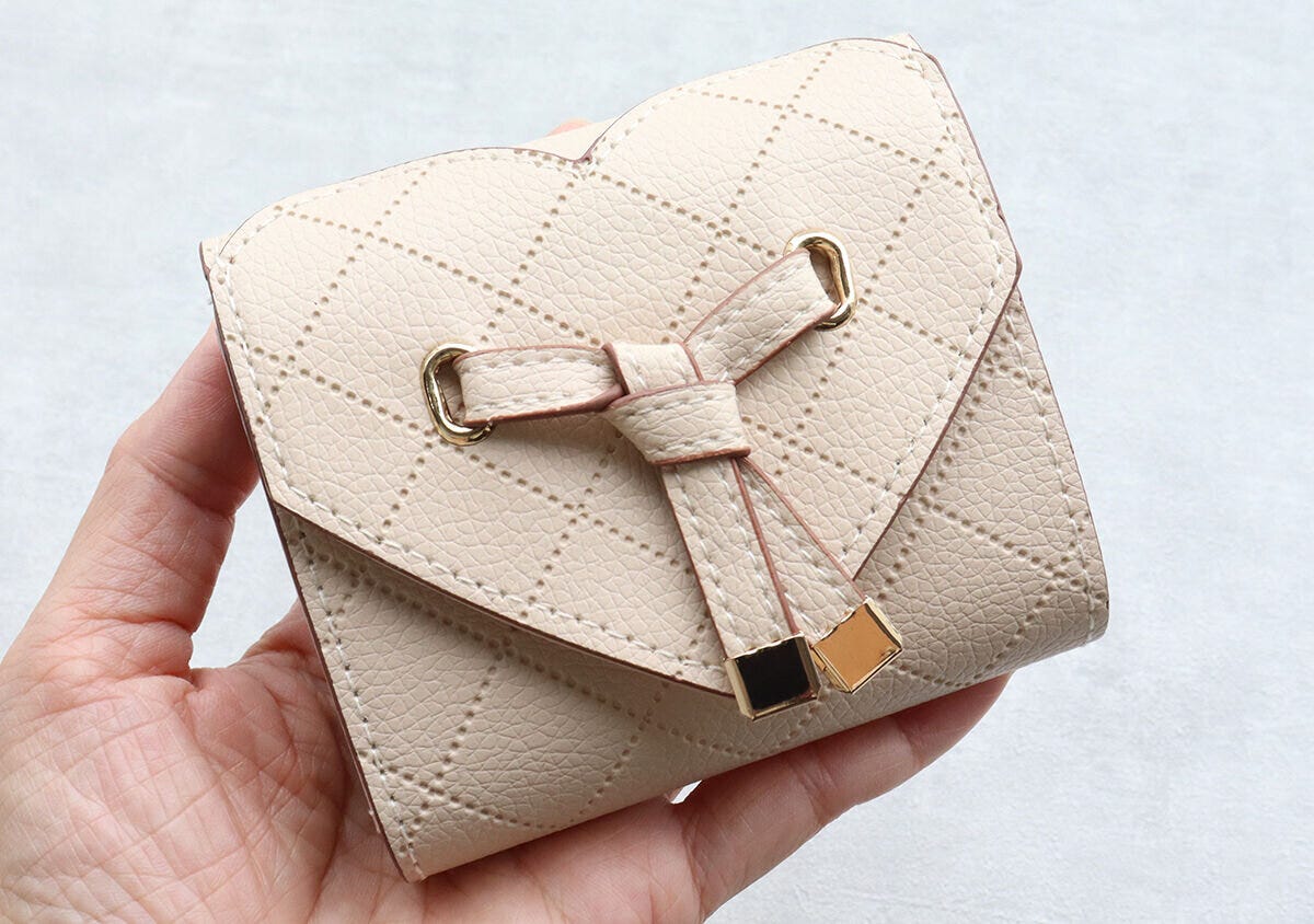 手のひらに乗せられたベージュのVISハートカットミニ財布
