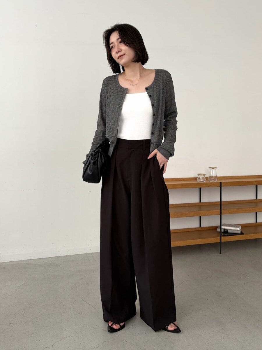 ショートヘアの女性がグレーカーデと黒ワイドパンツを着る