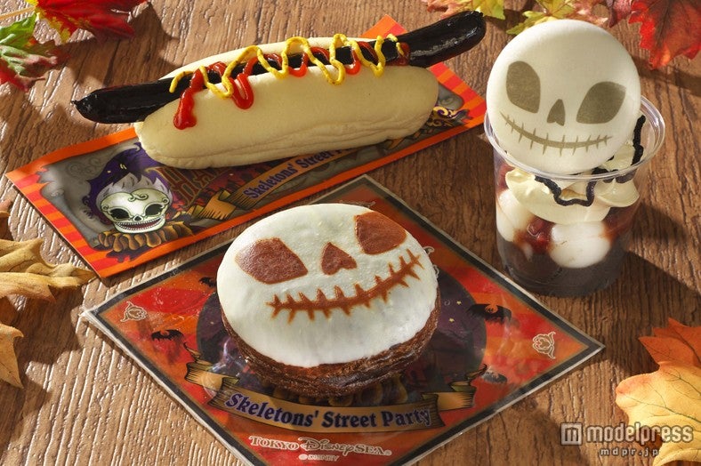 スケルトンメニュー集合／（写真右中央）スプーキースケルトンサンデー、（写真手前）スプーキースケルトンドーナツ、（写真奥）ブラックソーセージドッグ（C）Disney