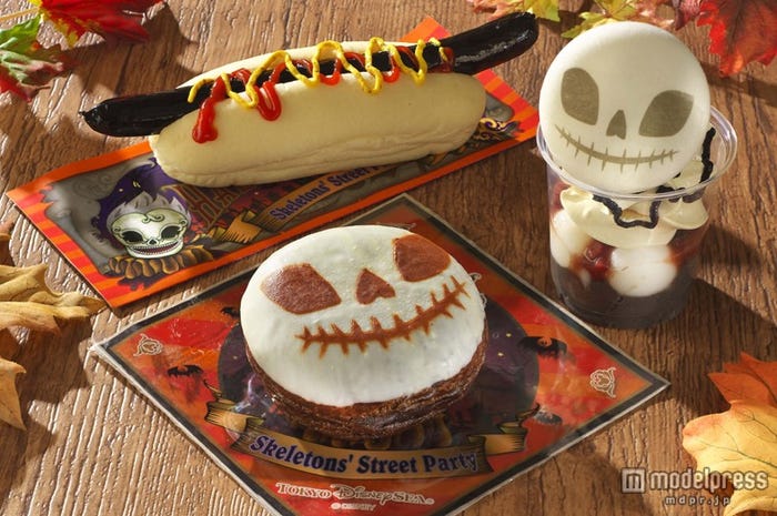 スケルトンメニュー集合/(写真右中央)スプーキースケルトンサンデー、(写真手前)スプーキースケルトンドーナツ、(写真奥)ブラックソーセージドッグ(C)Disney