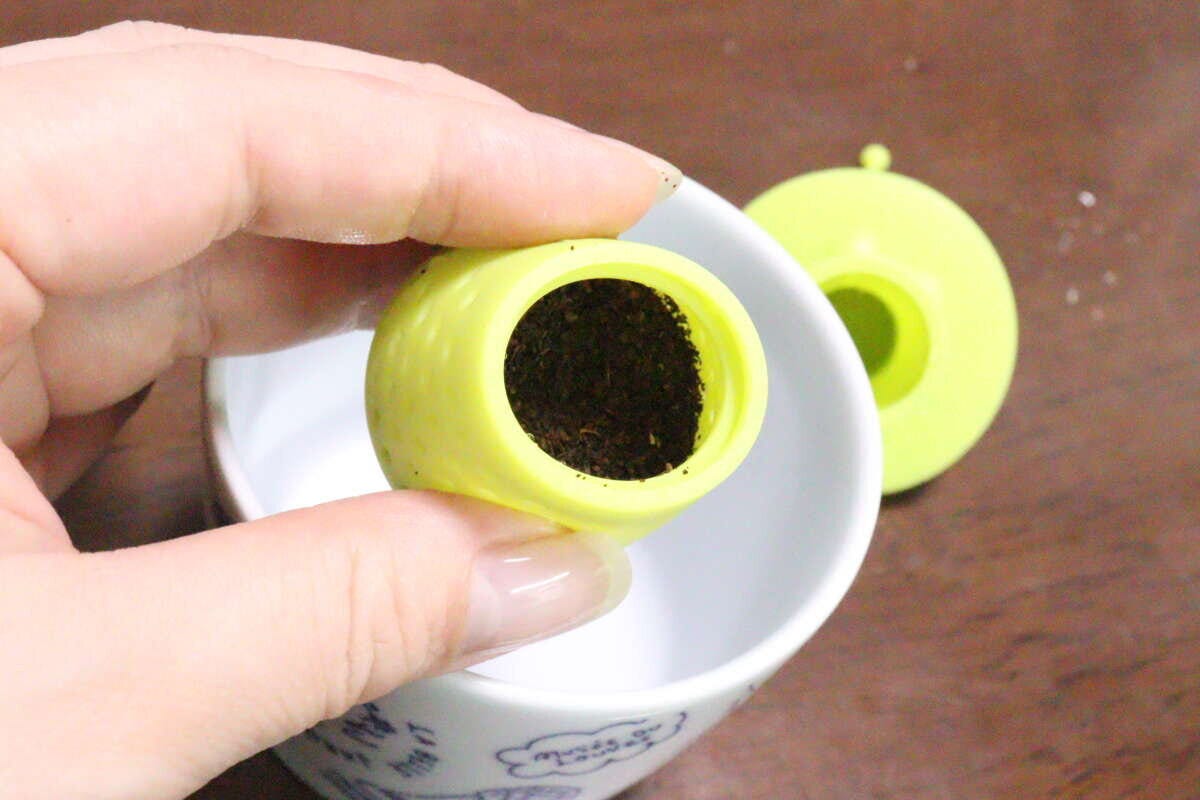 女性の指がティーストレーナーの下部に茶葉を入れている様子 女性の指がティーストレーナーの下部に茶葉を入れている様子