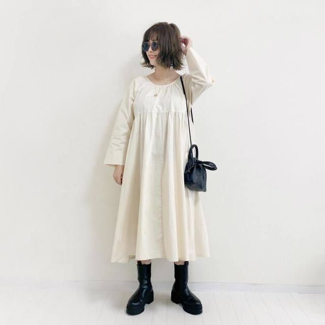 白のフレアワンピに黒のショルダーバッグを合わせショートブーツ、サングラスをコーディネート