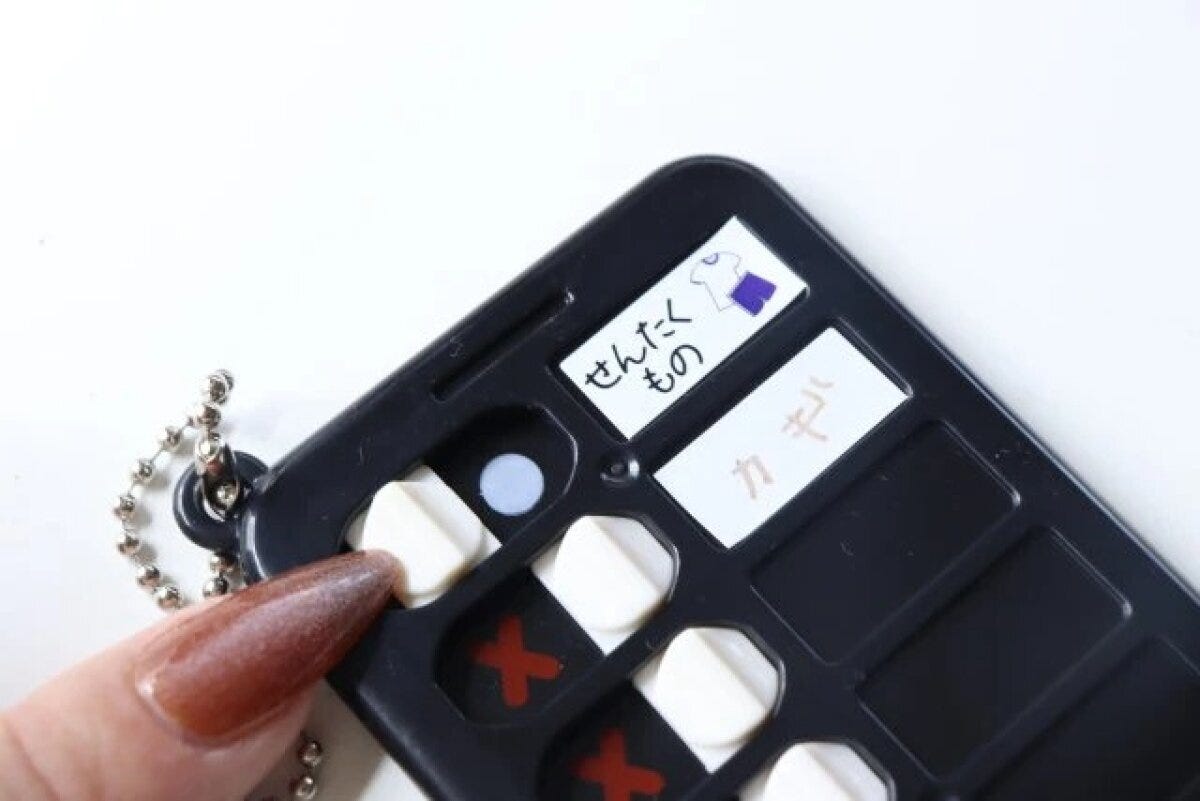 黒いチェッカーキーホルダーに「せんたくもの」「カギ」と書かれたシールが貼られている