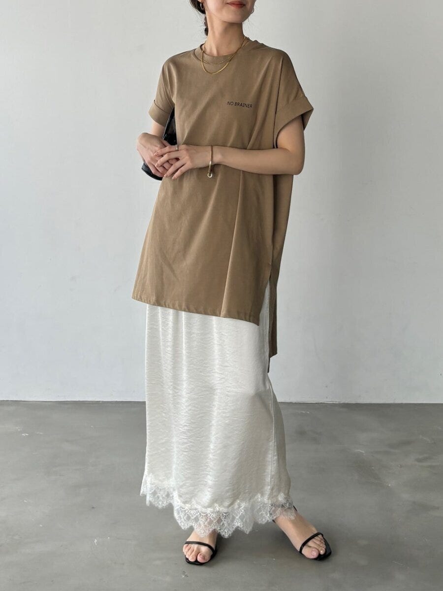 茶色のチュニックTシャツと白のレース裾ナロースカートを着用した女性の全身 茶色のチュニックTシャツと白のレース裾ナロースカートを着用した女性の全身