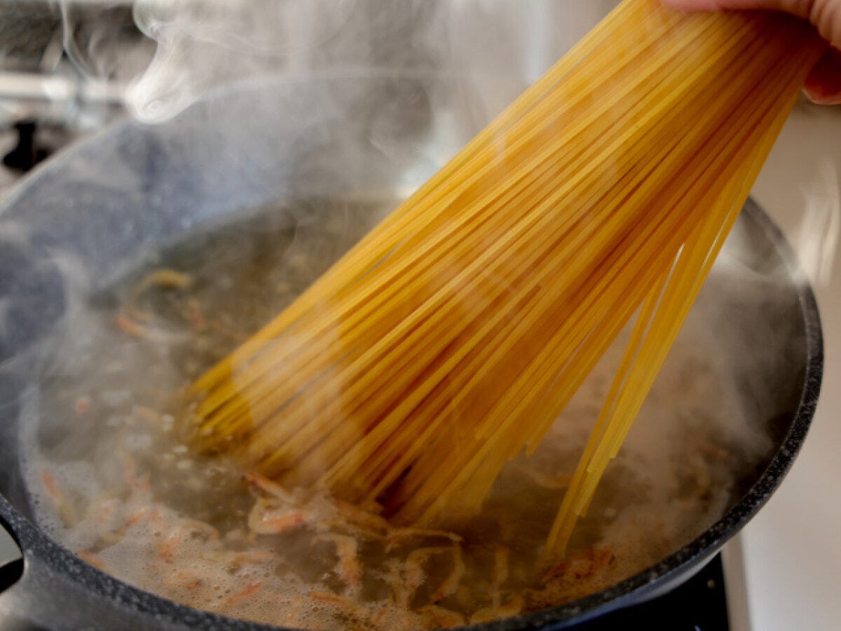 煮立ったフライパンにスパゲッティを束のまま入れている工程写真