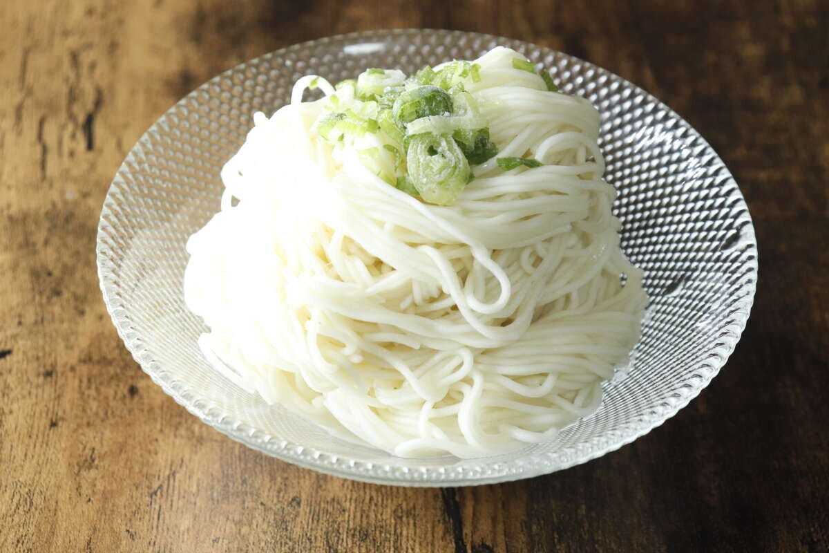 ガラスの器に盛られた白いそうめんと刻みネギ ガラスの器に盛られた白いそうめんと刻みネギ