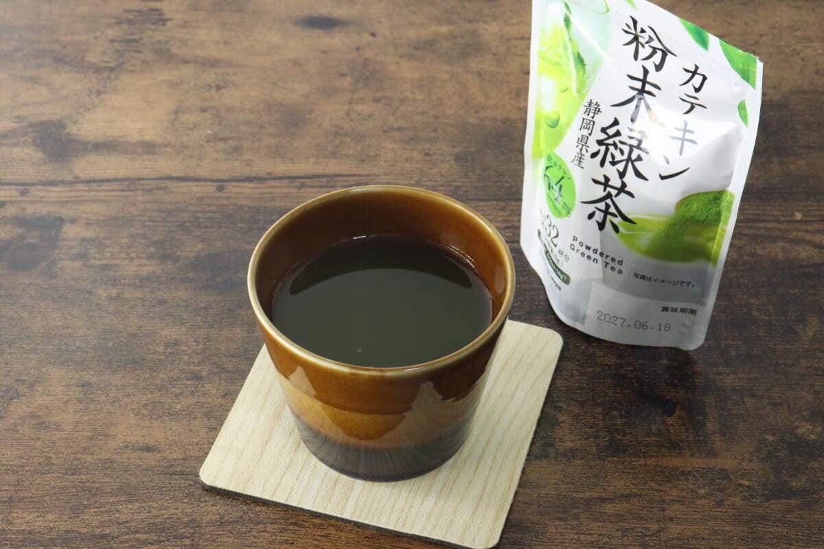 茶碗に入った濃い緑色の緑茶と、奥に「カテキン粉末緑茶」パッケージ 茶碗に入った濃い緑色の緑茶と、奥に「カテキン粉末緑茶」パッケージ