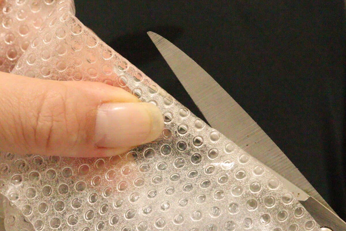 ハサミで冷蔵庫マットをカットしている手元のクローズアップ