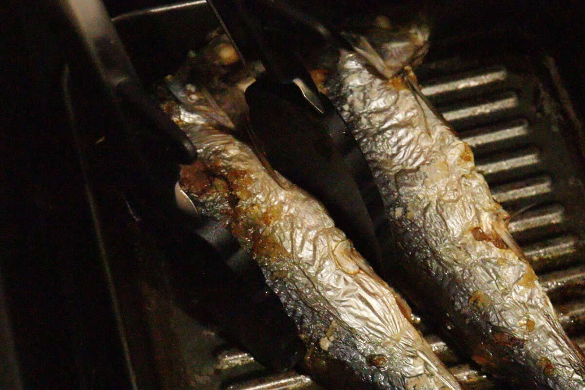 グリルで焼かれた焼き魚をシリコーントングで掴んでいる