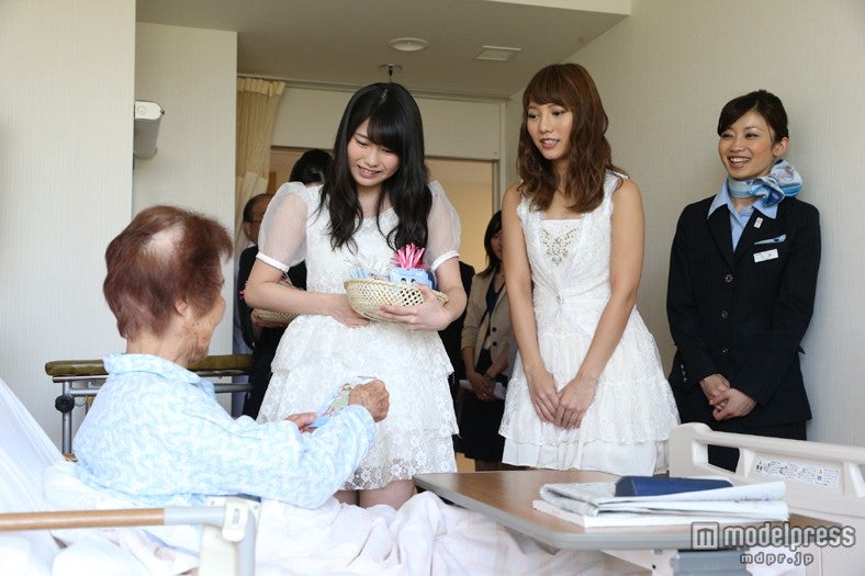 入院している患者へ「すずらんの花」を贈呈したAKB48（左から：横山由依、高城亜樹）とANA客室乗務員