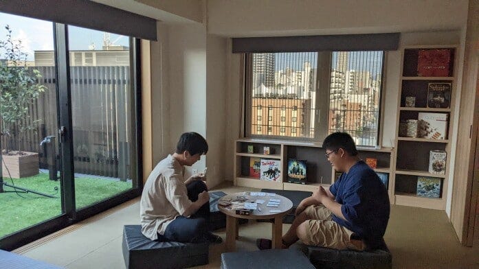 チェックインしたとたん、棚のボードゲームを始める大学生（MIMARU大阪 難波STATION）