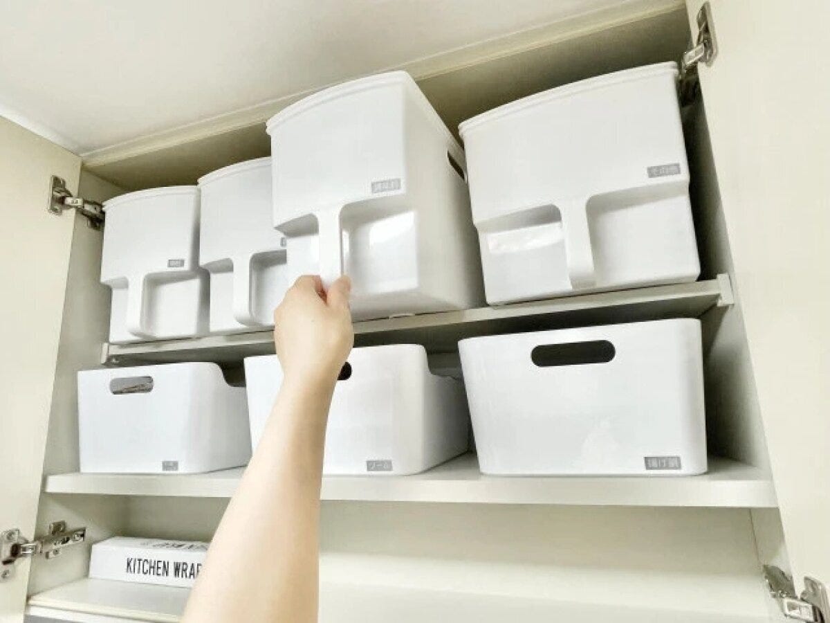 キッチンの吊戸棚に取っ手付きの白い収納ボックスがきれいに並んでいる状態
