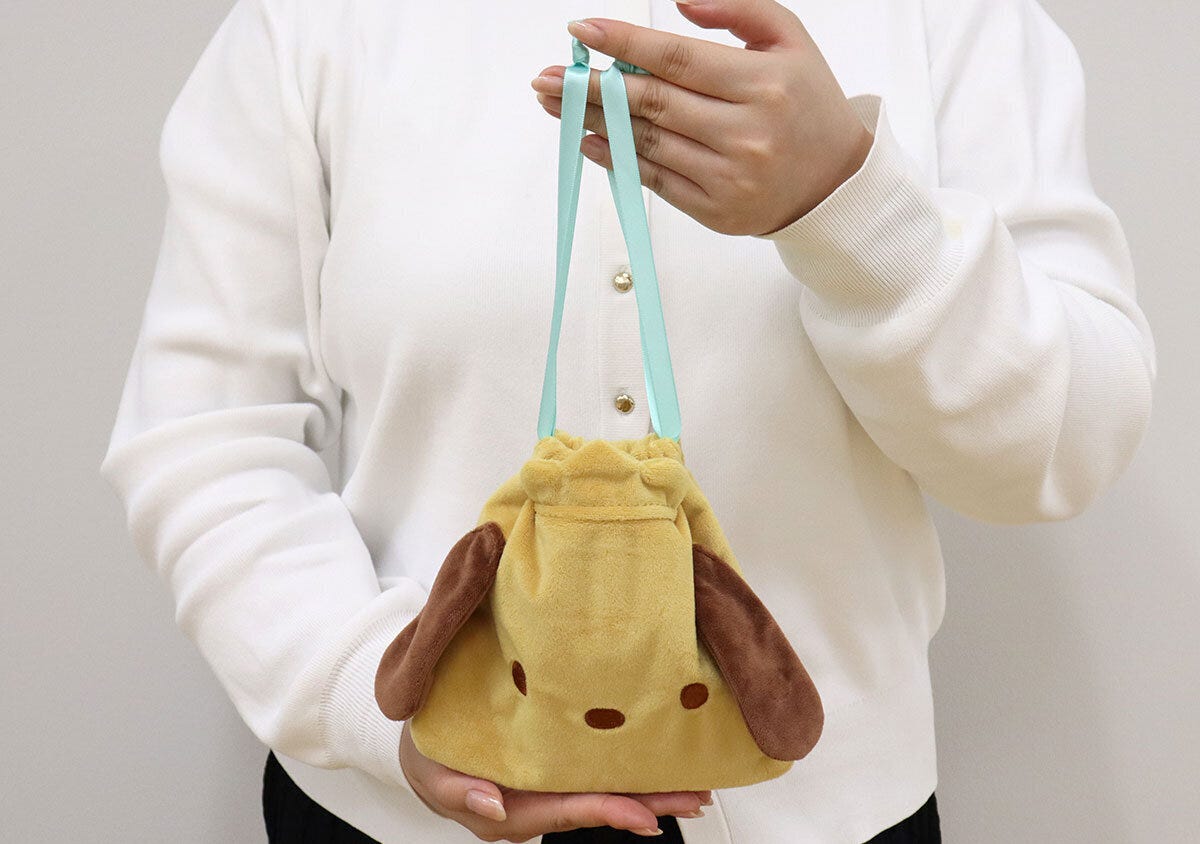 白い服の女性がポチャッコの巾着ポーチを手に持っている