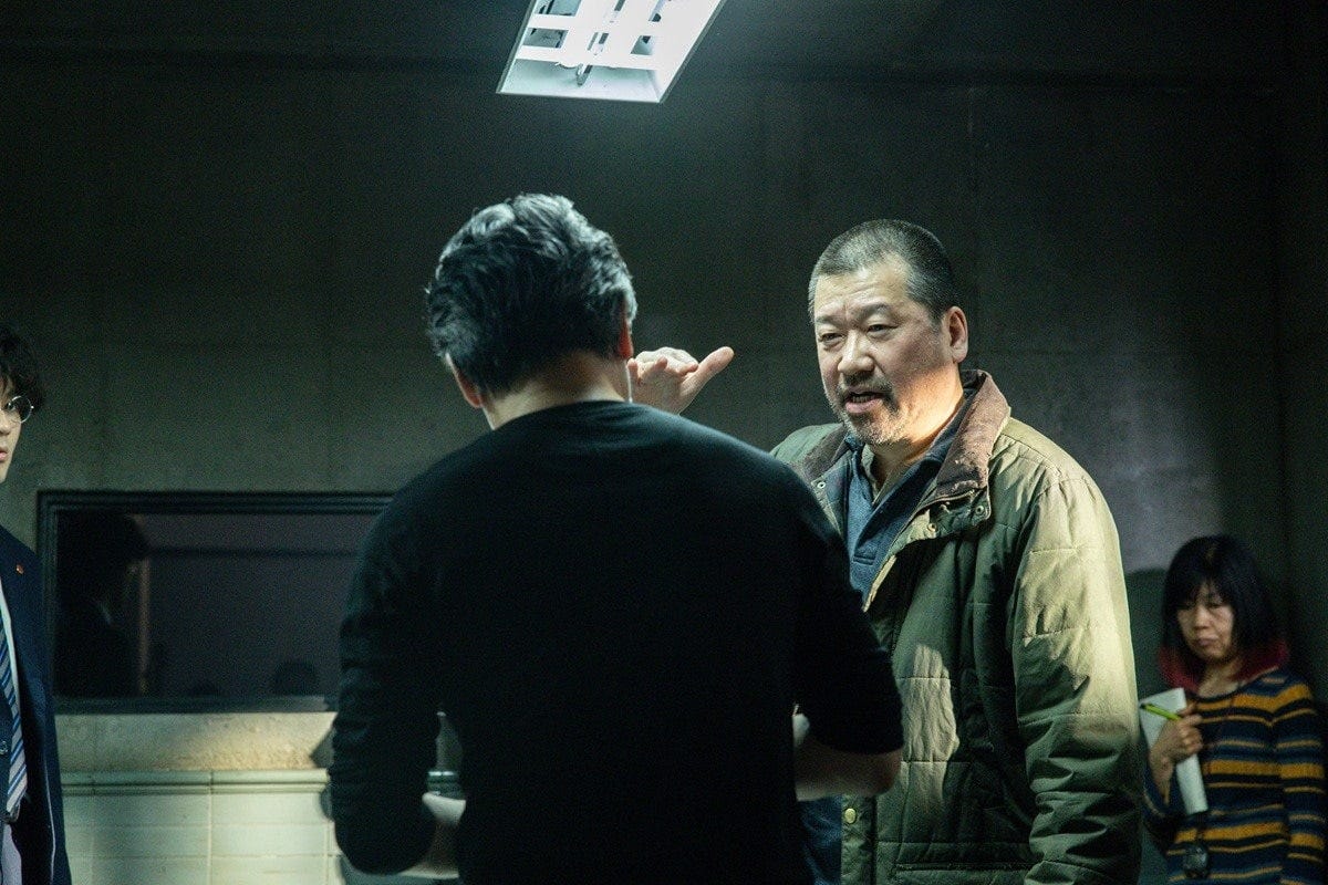 メイキング:監督と話し合うスズキタゴサク役の佐藤さん (c)呉勝浩/講談社