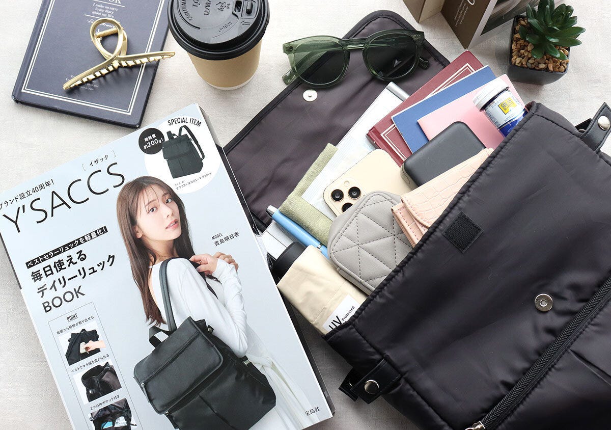 ムック本と荷物を入れたリュックを小物と並べて俯瞰で撮影した写真