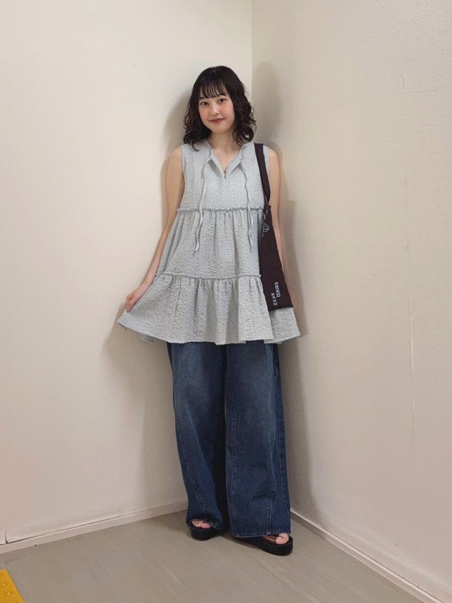 ブルーのティアードチュニックと濃いめワイドデニムの女性 ブルーのティアードチュニックと濃いめワイドデニムの女性