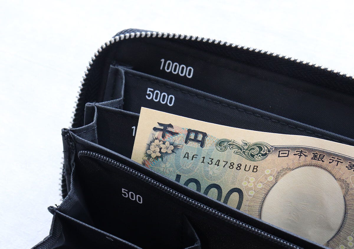 開いた長財布のお札入れに千円札、仕切りに金額表示