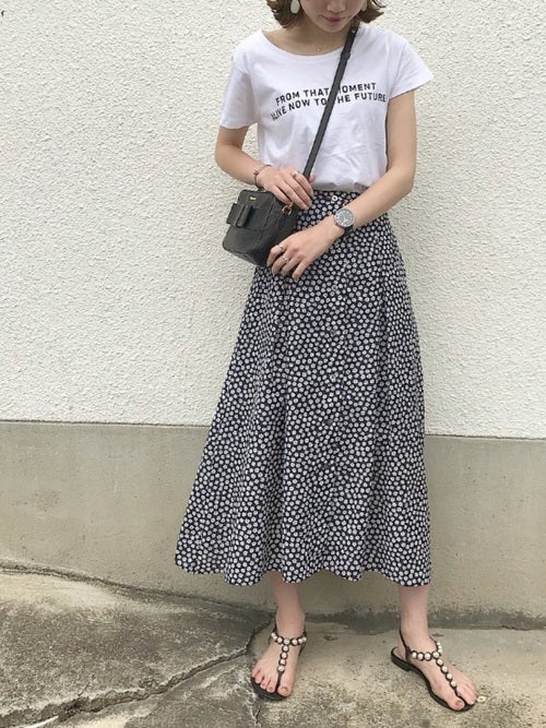 ロゴTシャツに柄スカートを履いた女性