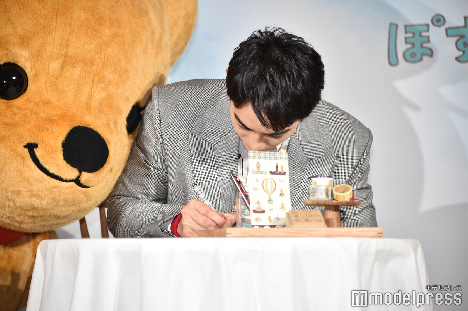 祖母に手紙を書いている町田啓太に近づくぽすくま（C）モデルプレス