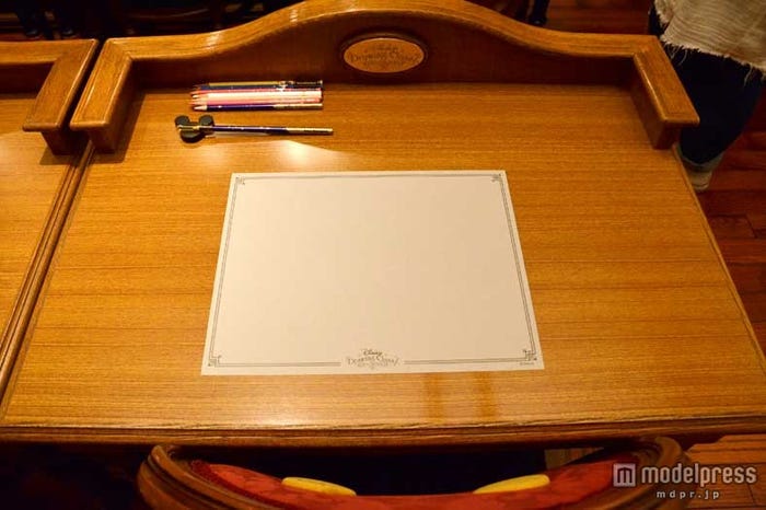 机の上にはグレイの紙と鉛筆、色鉛筆などが用意されている/「ディズニードローイングクラス」