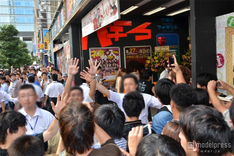 劇場の裏口に殺到するファンを制止するスタッフ