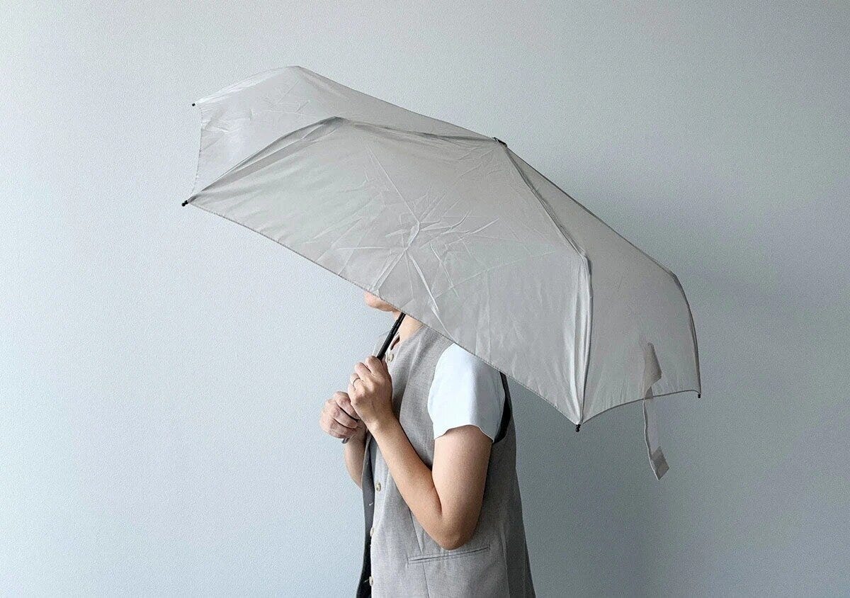 グレーの折りたたみ傘を差している人物の横顔