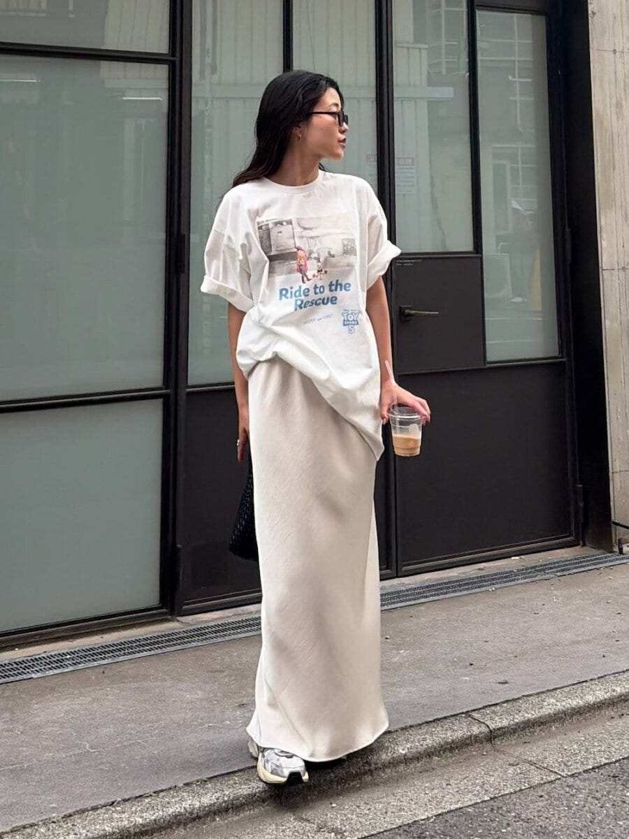 白いプリントTシャツとサテンスカートで立つ女性 白いプリントTシャツとサテンスカートで立つ女性