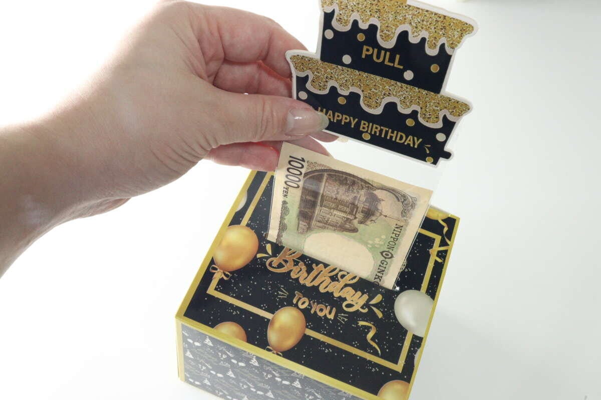 ケーキ部分を引っ張ると1万円札が出てくる様子