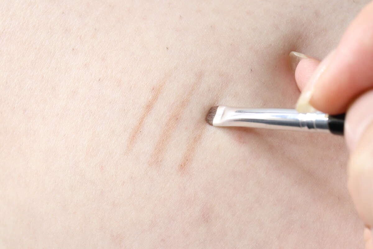 腕にアイライナーブラシで薄い茶色のラインを引く様子 腕にアイライナーブラシで薄い茶色のラインを引く様子