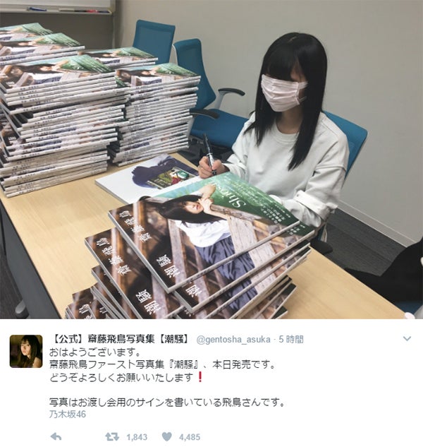 サインを書き入れる齋藤飛鳥／写真集「潮騒」公式Twitterより