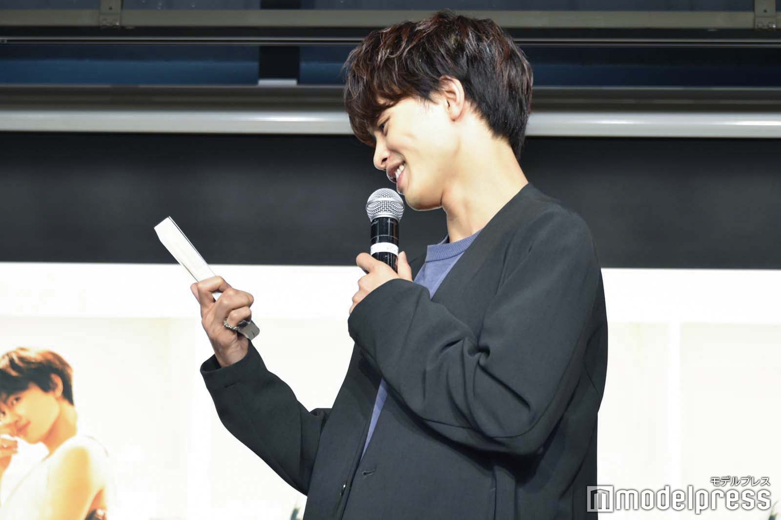 フォトブックの点数をつける草川拓弥（C）モデルプレス