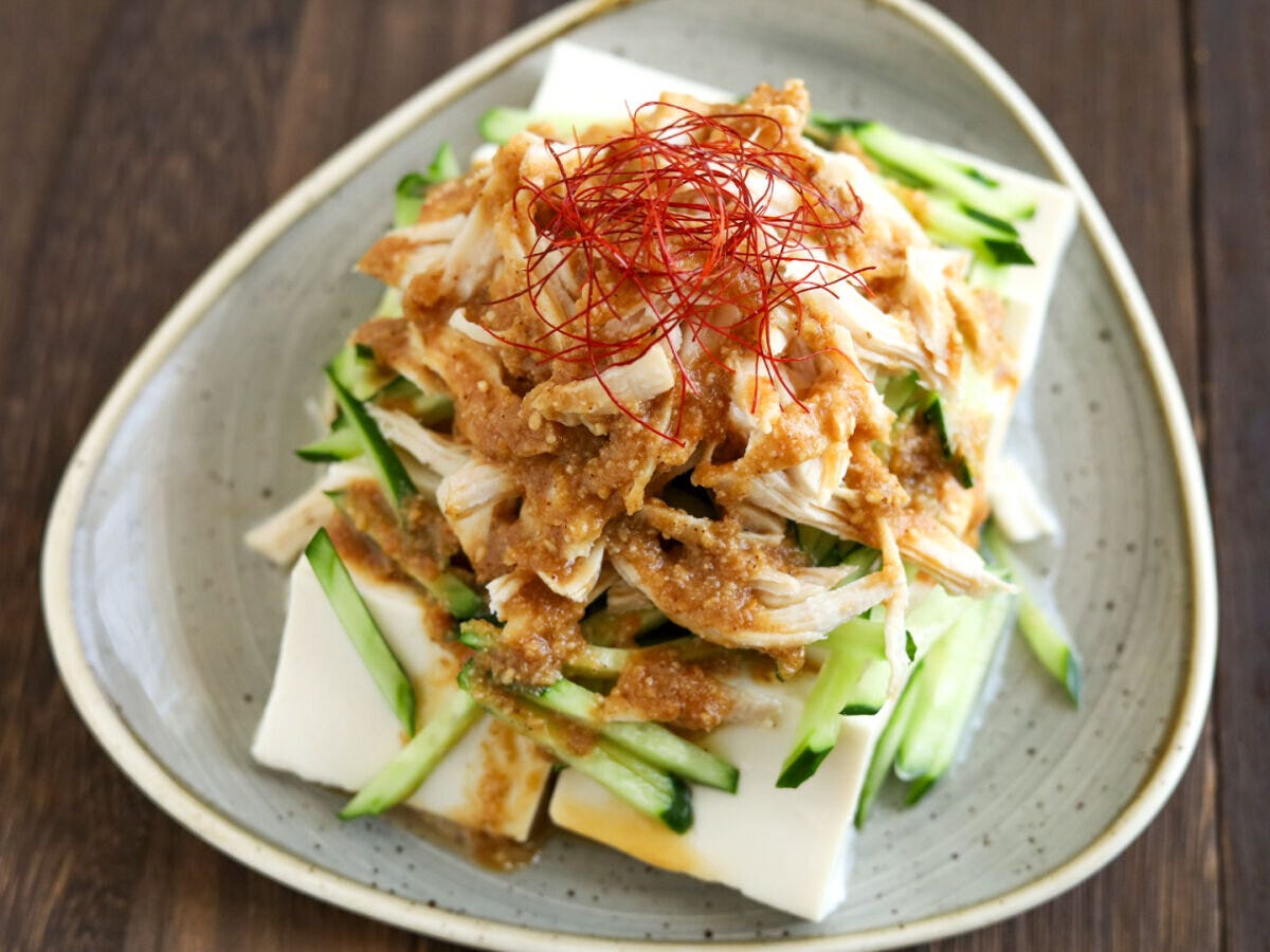 豆腐の上にきゅうり、ほぐした鶏肉、ごまだれ、糸唐辛子が盛り付けられた棒々鶏のせ冷奴