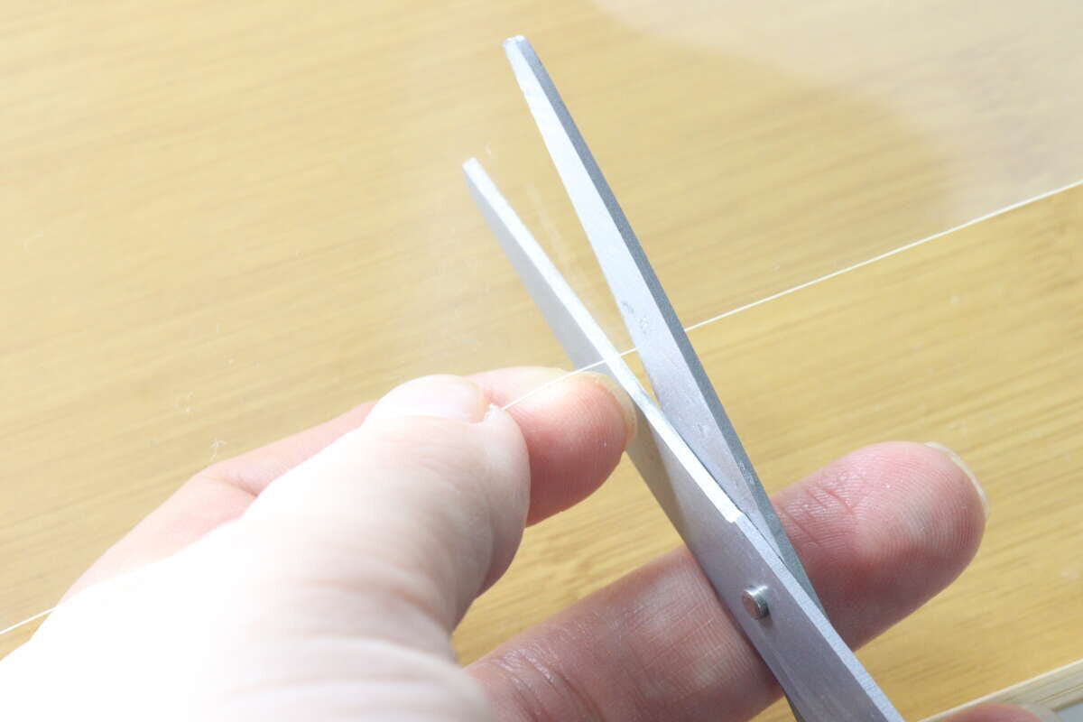 ハサミで透明な粘着ゲルシートをカットしている手元