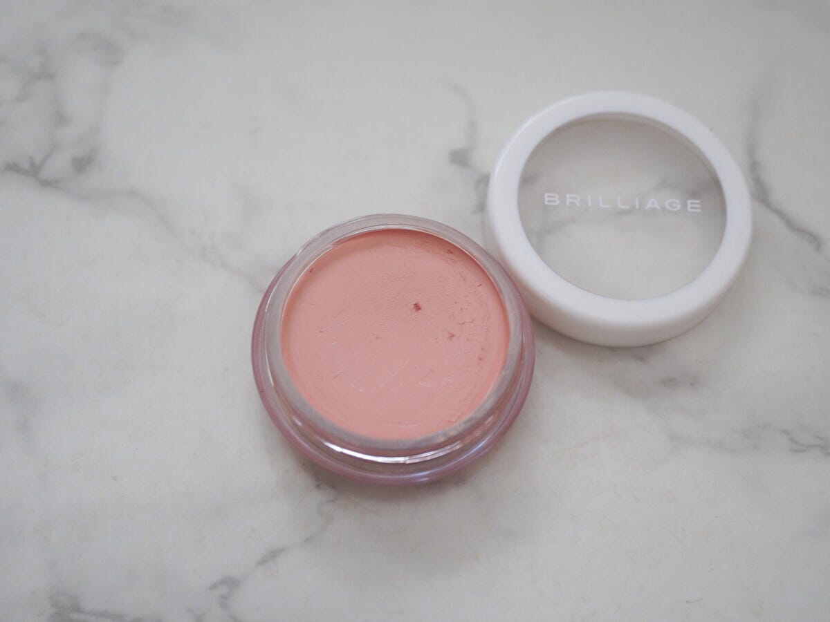 BRILLIAGEのピンクベージュのコンシーラーチーク、透明な容器の蓋を開けた状態で大理石の上に置いた俯瞰