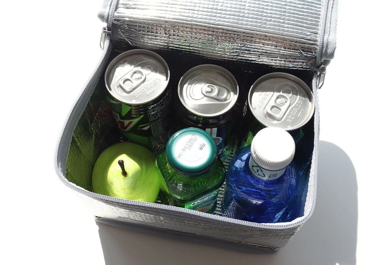 コールマンのシルバーアルミバッグ内部に缶ドリンク・フルーツ・ペットボトルが詰まっている俯瞰写真 コールマンのシルバーアルミバッグ内部に缶ドリンク・フルーツ・ペットボトルが詰まっている俯瞰写真