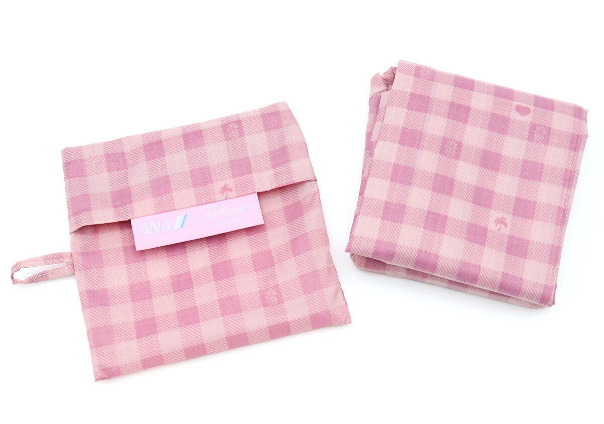 ANAロゴタグ付きのピンクの共布ポーチと折りたたんだエコバッグ本体を並べた白背景の写真